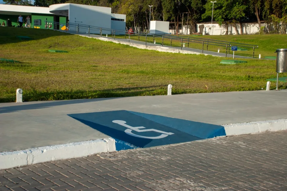 Blue sidewalk curb cut painted with white accessibility symbol.